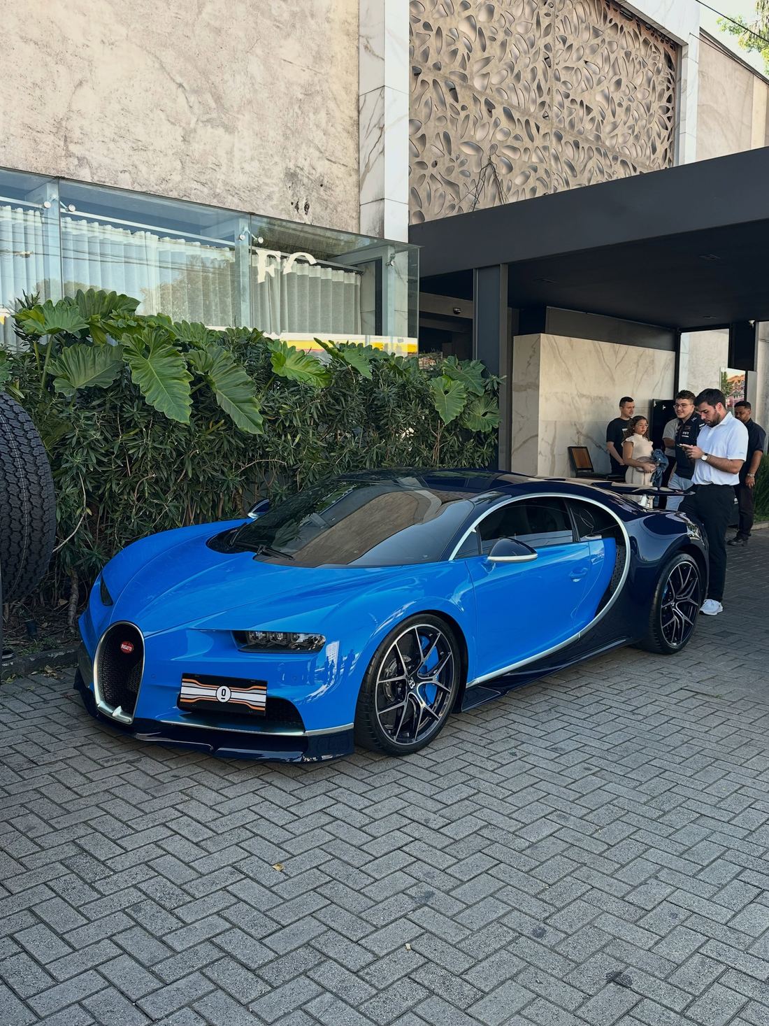 Bugatti Chiron Sport azul de dois tons estacionado numa calçada de São Paulo, com pessoas em volta olhando o carro